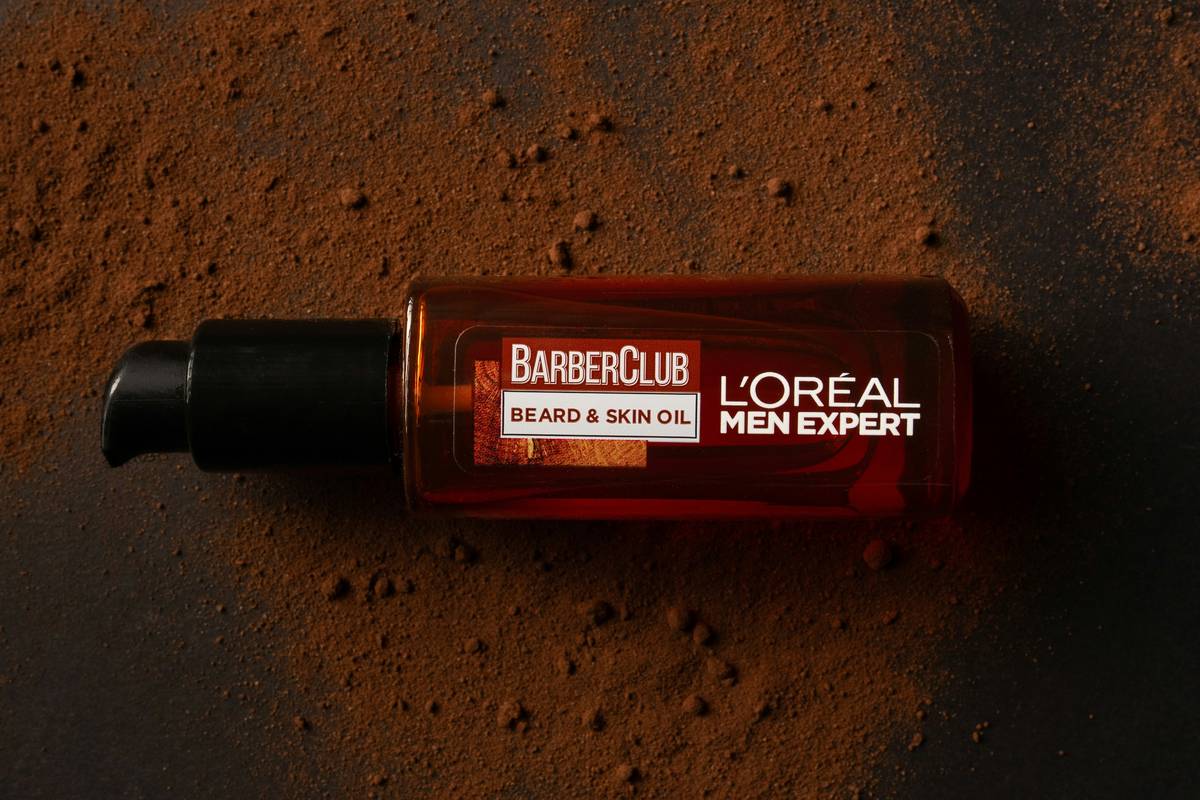 Close-up of a man applying organic beard moisturizing oils to his beard with dropper bottle
